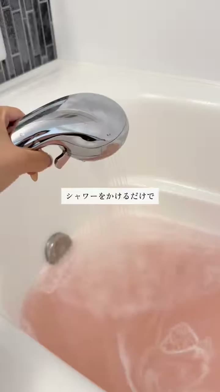 ピンク色のお湯をはった浴槽に、シャワーのお湯を当てている様子