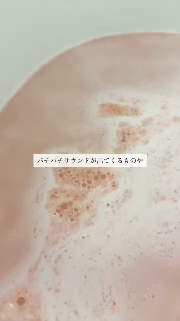 ピンク色のお湯の湯面に、小さな泡のつぶが集まっている様子