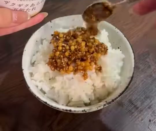 白いご飯の上に、スプーンでザクザクあられ万能たれをのせている様子