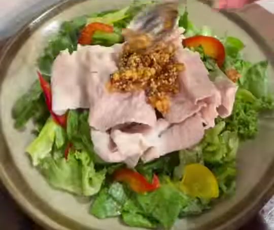 葉野菜と薄切り肉のサラダの上に、ザクザクあられ万能たれをのせている様子
