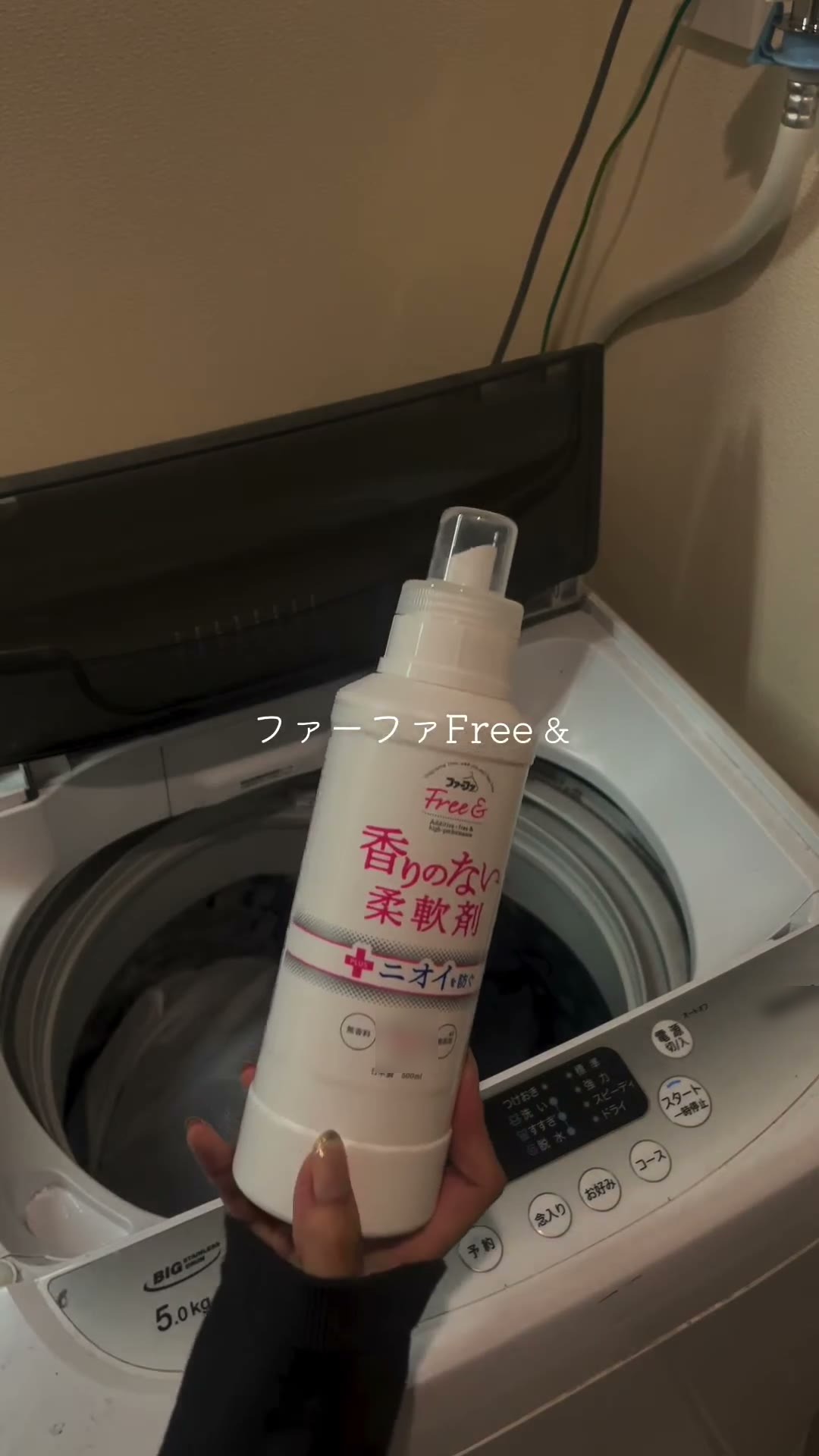 ふたを開けた縦型洗濯機の前で、ファーファ フリー＆の柔軟剤の白いボトルを手に持っている場面
