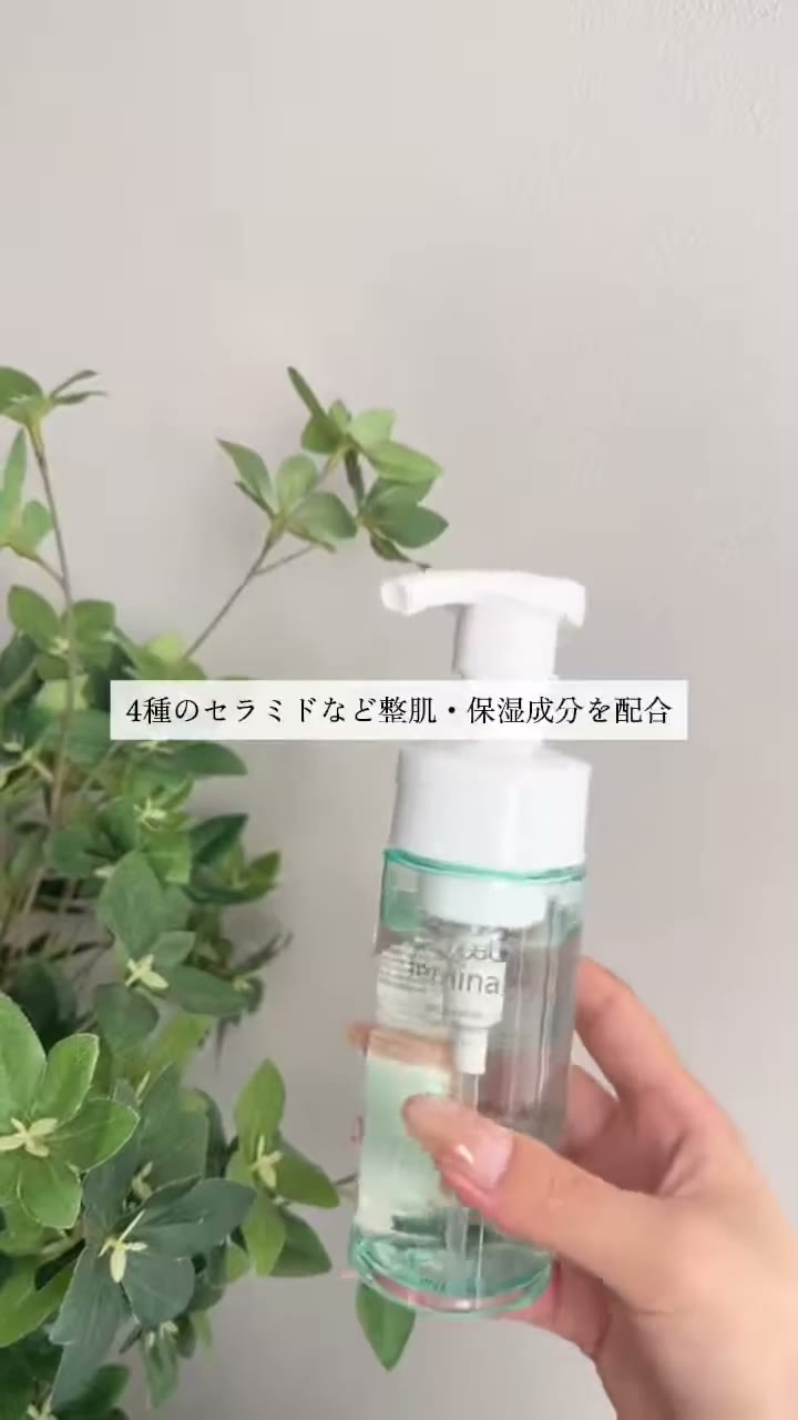 グリーンの植物の前で、透明なミントグリーンのボトルを手に持っている場面