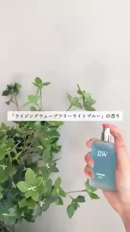 RWのロゴが入った青い香水のボトルを手に持っている様子
