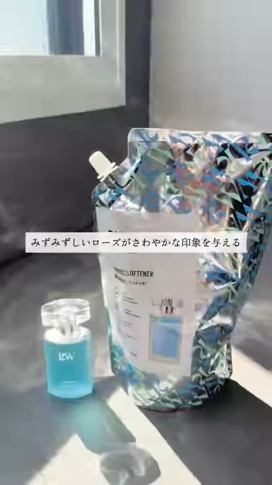 窓辺の台に、柔軟剤の詰め替え袋と青い小瓶が並んでいる様子