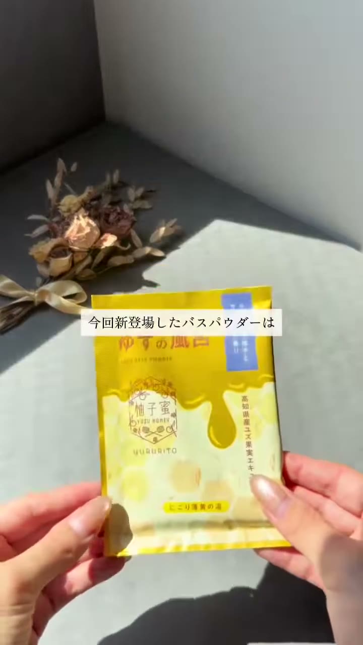 グレーの台の前で、柚子蜜と書かれた黄色い袋を両手で持っている場面