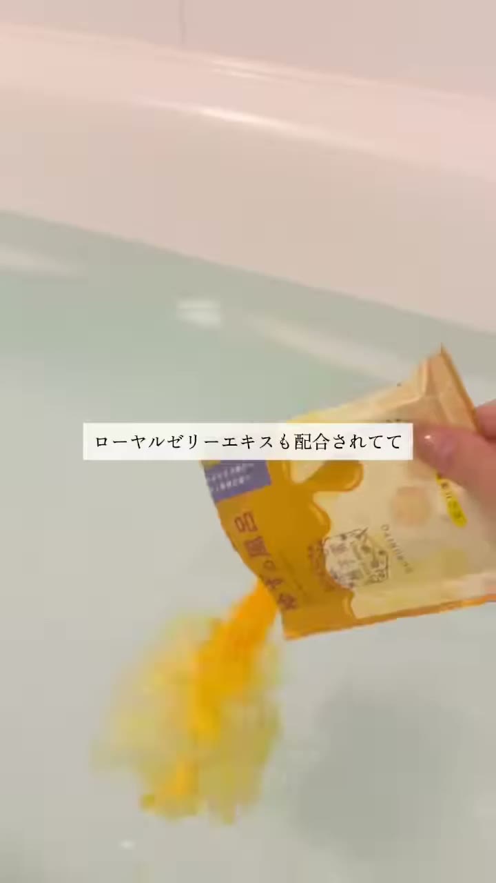 白い浴槽のお湯に、袋から黄色のパウダーを入れている場面