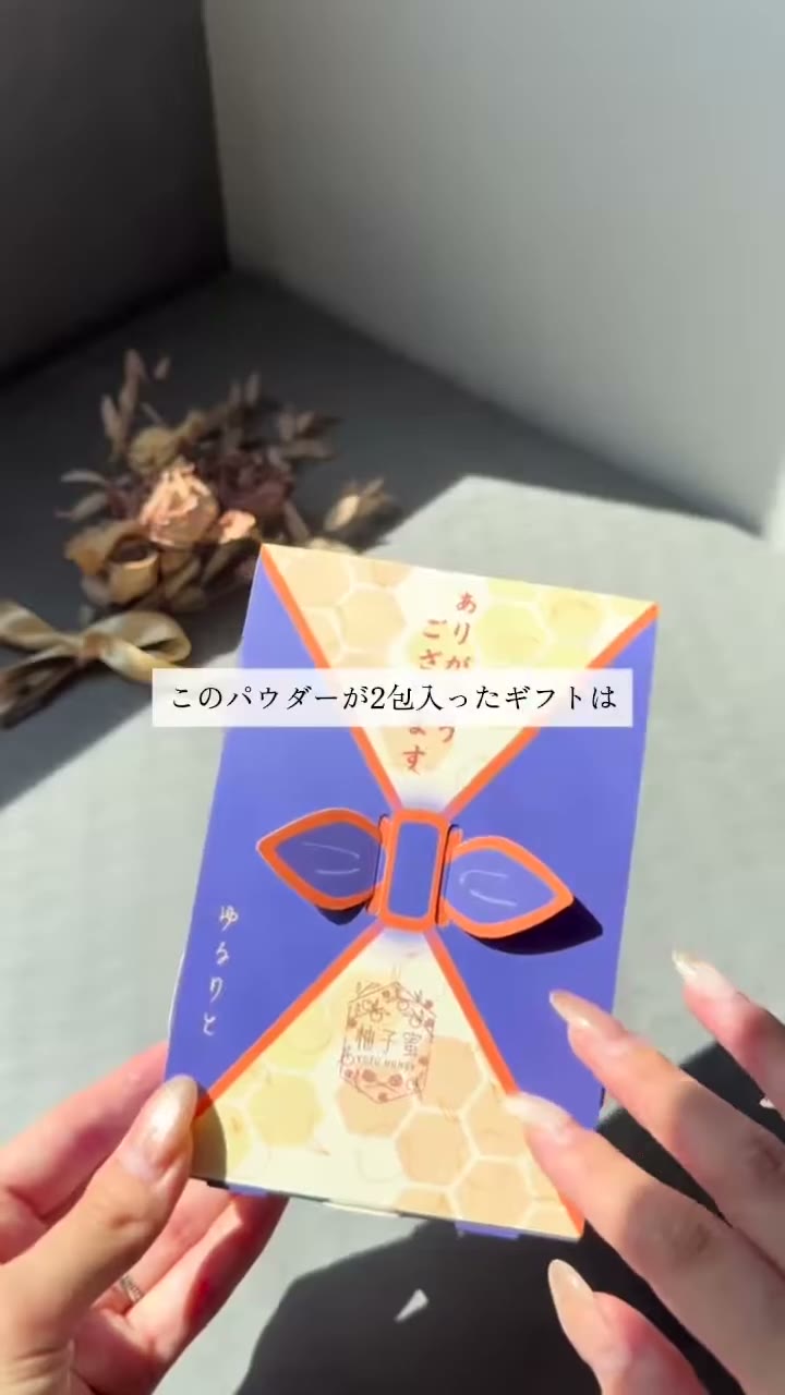 「ありがとうございます」の文字と柚子蜜のロゴが入った、青紫とオレンジの箱を手に持っている場面